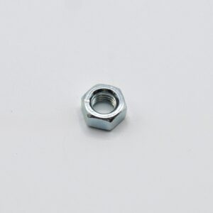 Metal hex nut resting on a light gray surface, showing interior threads and shiny metallic finish.