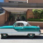 Vintage turquoise and white 1950s car parked in front of a brick building with '101 Lombard' sign on the wall.
